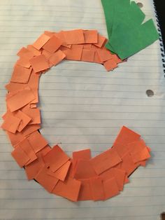 a paper wreath made out of orange and green pieces of construction paper on top of a piece of lined paper