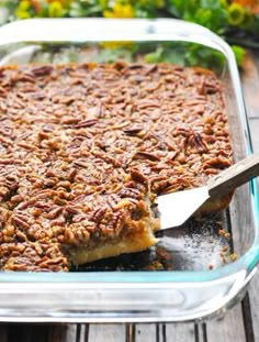 pecan pie in a glass casserole dish with a wooden spoon on the side