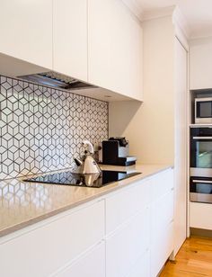 a kitchen with an oven, stove and counter top in white cabinetry next to a wooden floor