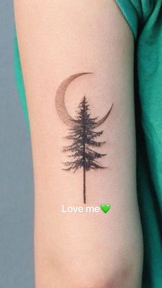 a woman's arm with a pine tree and crescent tattoo on it