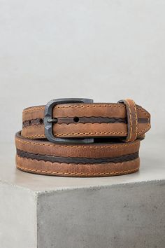 Made from genuine American bison leather, the durable Big Timber belt accents your outfit with rich detailing, from its burnished center coloring over a subtle tooled pattern to its distressed metal buckle with a patina finish. Contrast stitching throughout lends visual appeal, while flat, hand-painted edges and a blunt tapered tip that slides through a single leather keeper finish this handsome design. Lined with full-grain leather. Artisan Leather Belt Buckle With Antique Design, Rustic Leather Belt With Antique Buckle, Rugged Leather Belt Buckles In Distressed Brown, Rugged Distressed Brown Leather Belt Buckles, Rugged Leather Belt Buckle In Distressed Brown, Rustic Brown Hand-tooled Belt, Rugged Distressed Brown Leather Belt, Rustic Brown Hand Tooled Belt, Distressed Brown Leather Belt With Antique Buckle