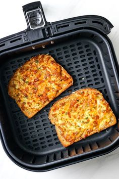 two pieces of pizza sitting on top of an air fryer