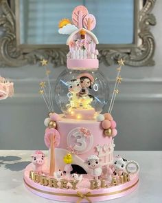 there is a pink cake with gold trimmings and decorations on the top tier