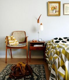 a bed room with a neatly made bed next to a chair and rug on the floor