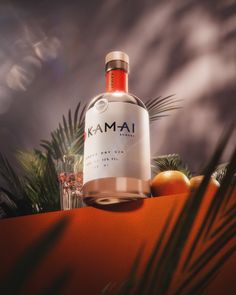 a bottle of kanmai gin is next to some oranges and palm leaves