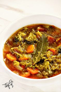 a white bowl filled with vegetable soup on top of a table