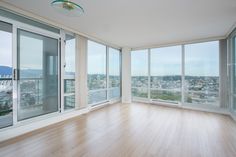 an empty room with wooden floors and large windows looking out onto the city below it