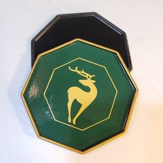 a green and black octagonal shaped box with a deer emblem on the front, sitting on a white surface