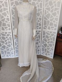 This early to mid 60s wedding dress is in the romantic Edwardian style with its high collarless neckline trimmed in lace, long sheer sleeves with very wide button and loop cuffs, has a lined bodice  with rows of lace and the waist is at the natural portion not rising higher to the front ( but not as high as empire line) The gown is lined in satin in the bodice and cotton in the skirt and has a back nylon zipper. It is labelled Terry Cooper original of Sydney in a size W equal to a modern medium White Vintage Wedding Dress For Ceremony, Vintage White Victorian Wedding Dress, White Long Sleeve Vintage Wedding Dress, Long Sleeve Lace Trim Wedding Dress, Regency Style Long Sleeve Vintage Wedding Dress, Victorian Long Sleeve Wedding Dress, Victorian Long Sleeve Dress With Fitted Bodice For Weddings, Vintage Long Sleeve Victorian Wedding Dress, Fitted Full Length Victorian Dress For Wedding