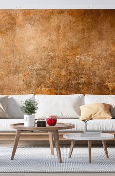 a living room with couches and tables in front of a large brown wall mural