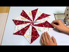 someone is working on a quilting project with red and white flowers in the center