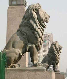 two statues of lions in front of a city skyline