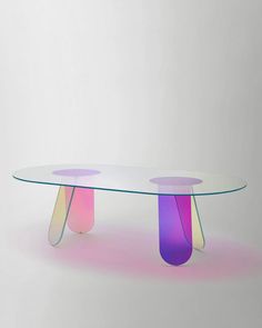 a glass table with two different colored sections on the top and bottom, sitting in front of a white wall