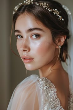 a woman wearing a bridal headpiece with pearls and beads on her hair is looking at the camera