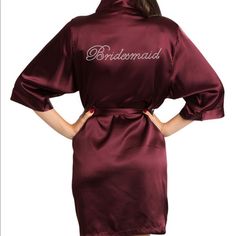 the bridesmaid robe is maroon with white lettering on it and has an open back