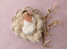 a newborn baby is wrapped in a white wrap with a flower on it's head