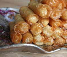 a pile of fried food sitting on top of a wooden table next to a spoon