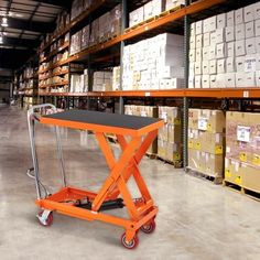 an orange scissor sits in the middle of a warehouse with boxes on shelves