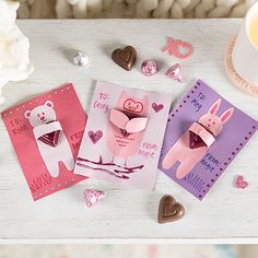 three valentine's day cards on a table with hearts and flowers in the background