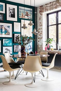 a dining room table with chairs and pictures on the wall in front of it's windows