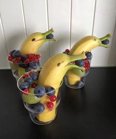 three cups filled with fruit and bananas on top of a table