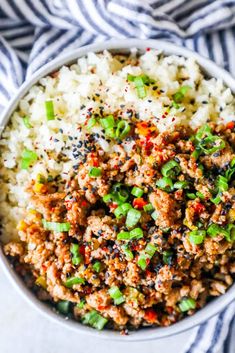 a white bowl filled with rice and ground beef on top of a blue and white striped towel