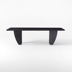 a black table sitting on top of a white floor next to a wooden bench with curved legs