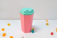 a pink cup sitting on top of a table next to gummy bears