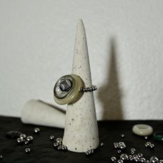 a ring is sitting on top of a white cone next to some beads and stones