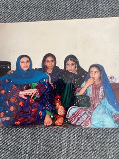 three women sitting next to each other in front of a wall