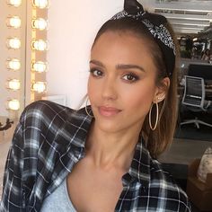 a woman wearing a black and white checkered shirt is posing for the camera with her hair in a bun