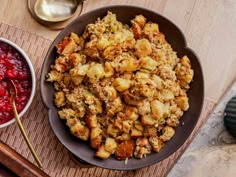 a bowl of stuffing next to a plate of cranberry sauce