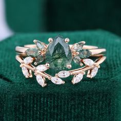 a close up of a ring on a green velvet surface with diamonds and leaves around it