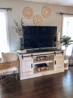 a flat screen tv sitting on top of a white entertainment center in a living room