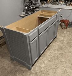 an unfinished kitchen cabinet with the doors open and christmas tree in the corner behind it