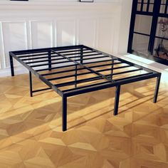 a bed frame in the middle of a room with wood flooring and white walls