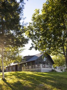 a large house sitting in the middle of a lush green field next to some trees