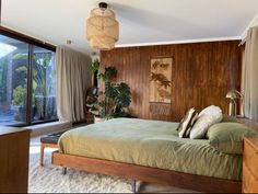 a bedroom with a large bed and wooden paneled walls next to a sliding glass door