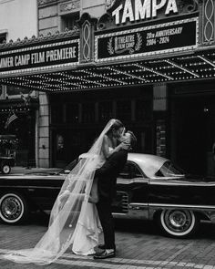 a bride and groom kissing in front of the tampa theater on their wedding day, circa 1950