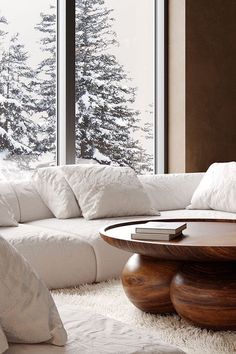 a living room with white furniture and large windows overlooking the snow covered trees in winter