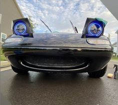 the front end of a black sports car with blue lights on it's headlights