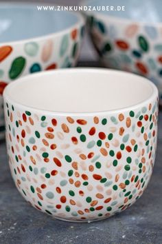 two bowls sitting on top of a table next to each other with different colored dots