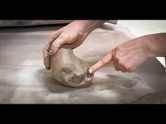 a person is making a vase out of clay