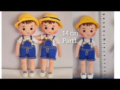 two crocheted dolls wearing blue overalls and yellow hats are next to a ruler