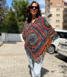 a woman is walking down the street wearing a colorful shawl