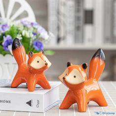 two ceramic foxes sitting on top of a white box