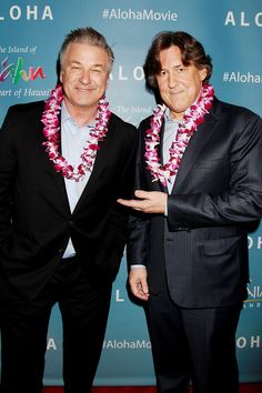 two men standing next to each other in front of a blue wall with the words aloha on it