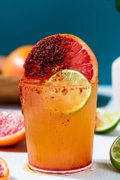 a close up of a drink with blood oranges and lime on the table next to it