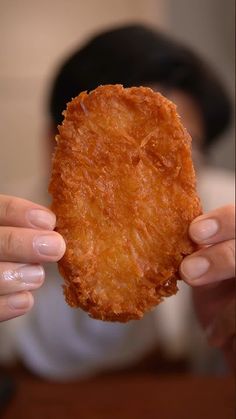 a person holding up a fried food item in their hands