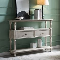 a table with two drawers and a lamp next to it in a room that has green walls